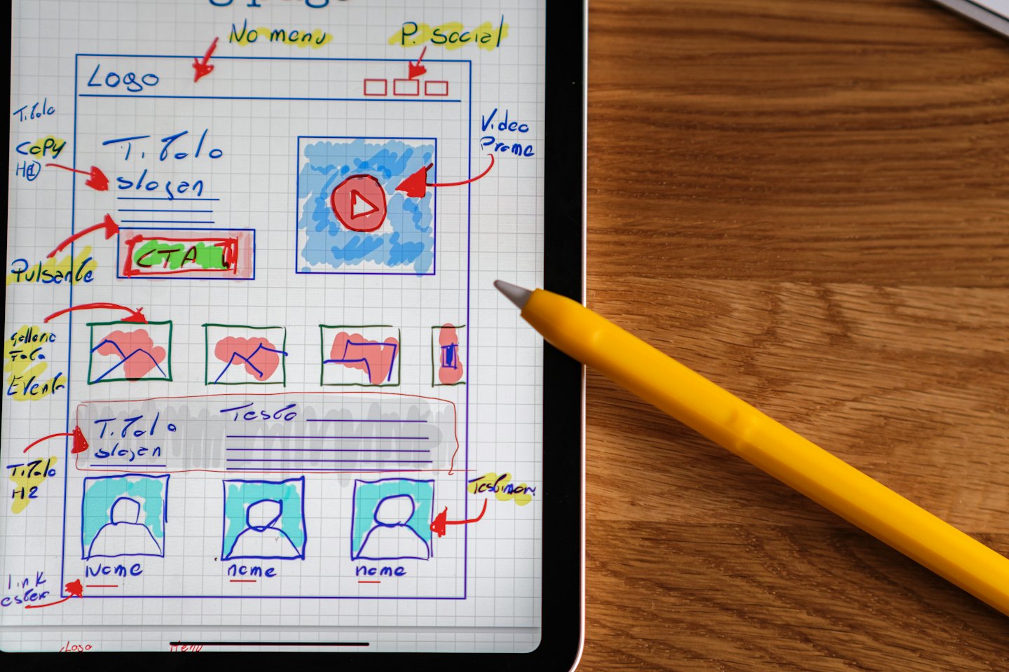 Digital tablet showing website wireframe sketches on a wooden table.